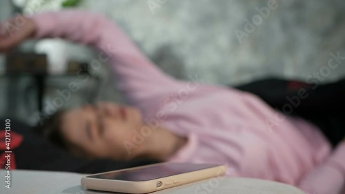 The girl wakes up in bed in a bad mood. Turns off the alarm on the phone