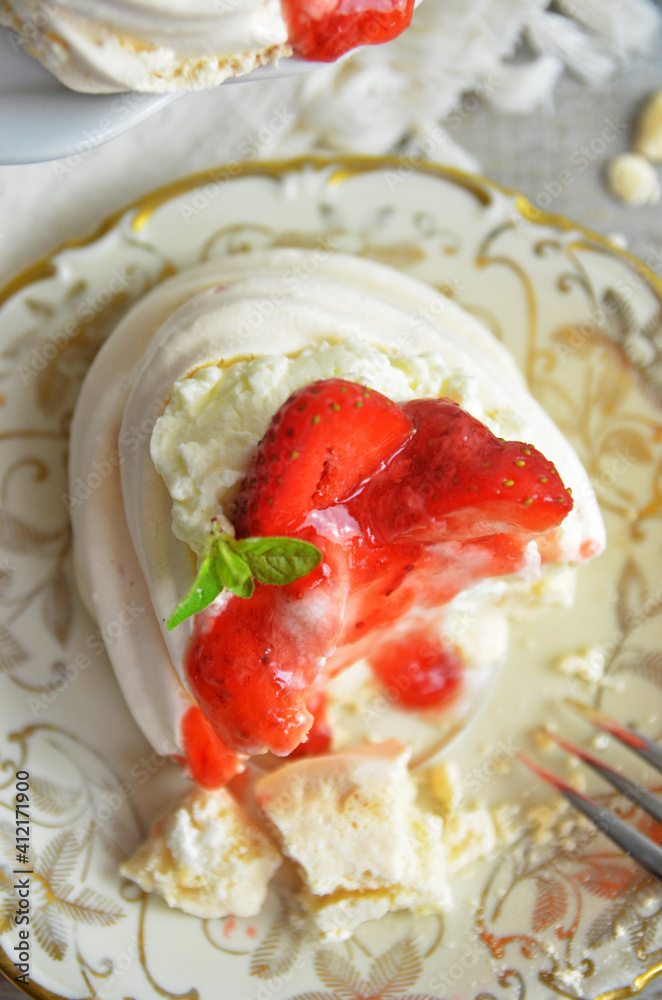 Mini meringue with strawberries poured with syrup on a rustic plate Mini meringue with strawberries poured with syrup on a rustic plate