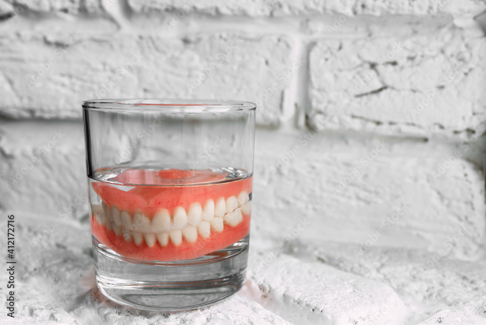 A denture in a glass of water. Dental prosthesis care. Full removable