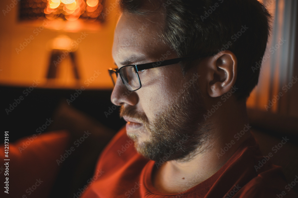 Portrait of attractive nerdy man is working late night on the computer in living room in home office Portrait of attractive nerdy man is working late night on the computer in living room in home office