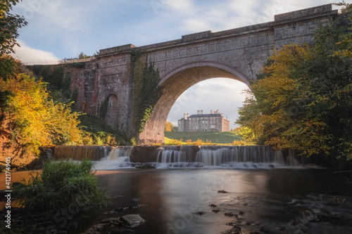Dalkeith Country Park with waterfall and arch framing manor house on a sunny autumn afternoon makes for an ideal day trip from Edinburgh in Scotland. photo