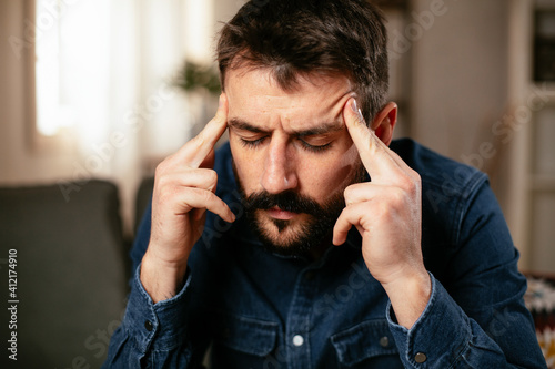 Sick man at home. Young man sitting on sofa having fever