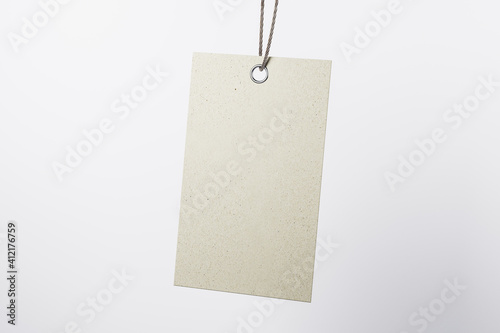 Blank beige eco label tag from recycled kraft paper on cotton twine at light empty background. Eco label tag concept. Mock up. 3D rendering