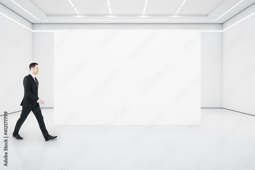 Businessman walking in minimalistic gallery interior Businessman walking in minimalistic gallery interior