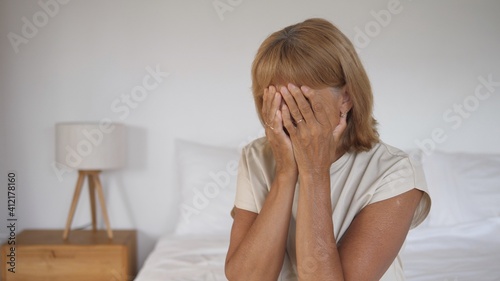 Portrait of frustrated middle aged Caucasian woman cries into hands