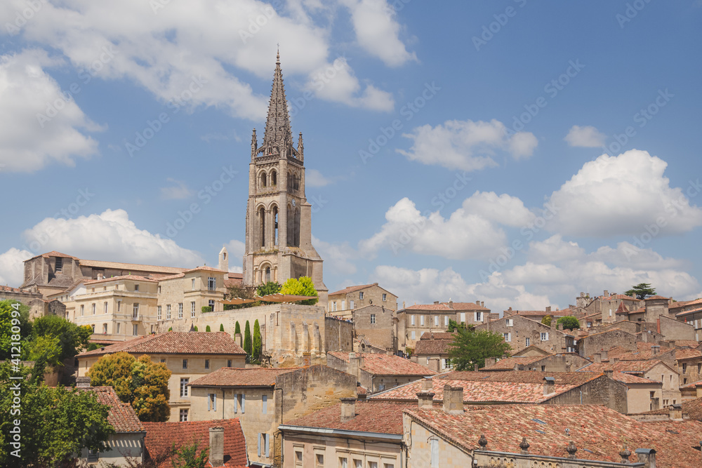A rooftop view over the Monolithic Church and village of Saint-Emilion in Bordeaux wine country on a sunny summer day.