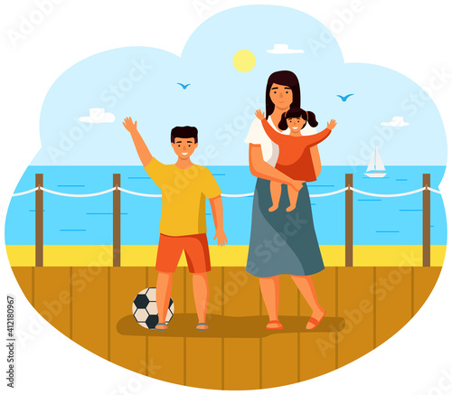 The mother stands with her children, a small child in her arms and a boy with soccer ball on the summer terrace on the seashore. The girl happily raises her hands. Woman is taking care of the baby