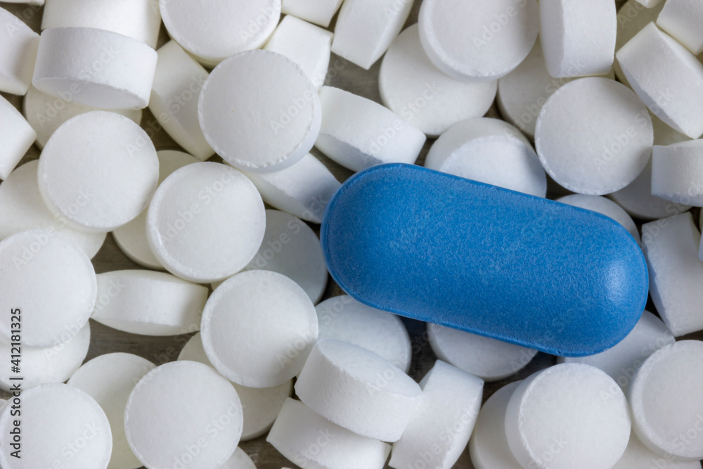 Blue oblong tablet on a background of white and round tablets close-up. Blue oblong tablet on a background of white and round tablets close-up.