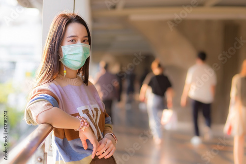 Asian woman in colorful sweater wears medical face mask in new normal and healthcare concept.