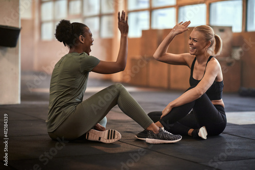 Fototapeta Naklejka Na Ścianę i Meble -  Laughing women high-fiving together after a workout