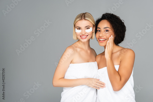 Φωτογραφία Positive multiethnic women in eye patches and towels isolated on grey
