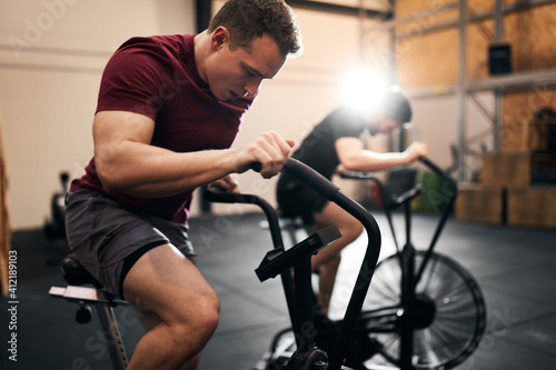 Two young men exercising on stationary bikes at the gym