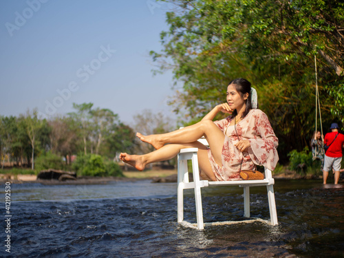 A woman sitting in a chair in the middle of the river © NaturyStocker