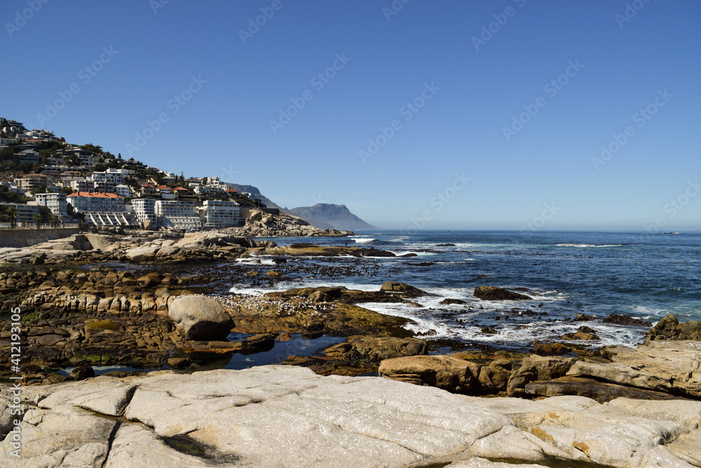 Rocks and the sea. Buildings on the slope of the hill overlooking the sea in Cape Town, South Africa.