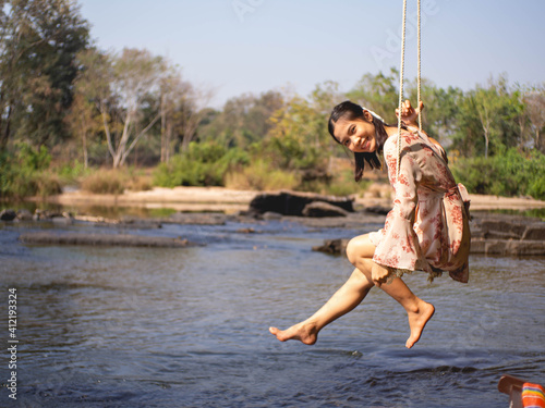 Fototapeta Naklejka Na Ścianę i Meble -  Woman on a wooden swing and a river