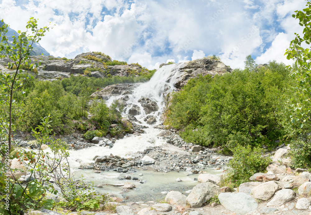 Beautiful waterfall. On a Sunny day the mountain stream flows among the forest . Panorama