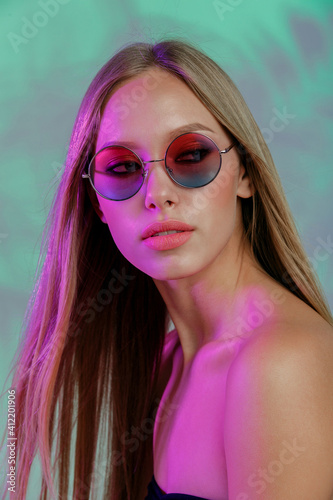 Attractive face of young woman in sunglasses. Exotic tropical background © RussianSaladeStudio