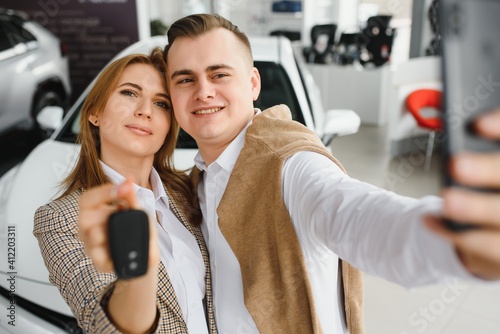 Young family making selfie in a car show room