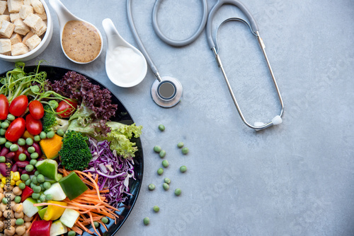 Health Care.  Fresh vegetable salad with medical stethoscope and equipment dumbbell for diet and weight loss for healthy care and protect virus,