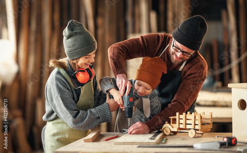 Happy family doing woodwork together in workshop photo