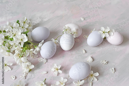 painted eggs and white flowers of a cherry tree on a light background. Easter still life in delicate colors.