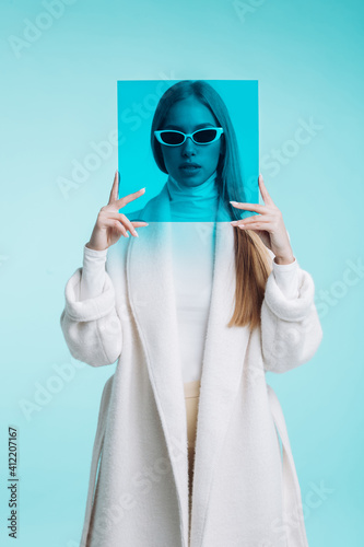 High fashion shot of model wearing casual coat and holding a square blue filter 