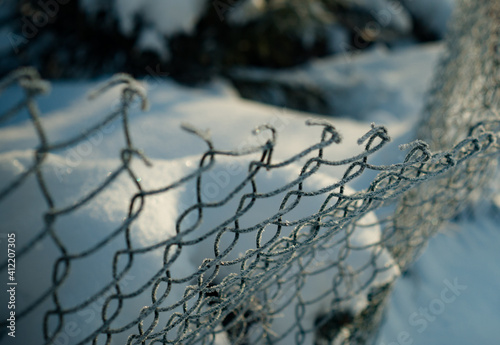 Frozen Fence Metal Mesh Snowy Hoarfrost  winter day. Winter snow texture Snow on Abstract Chainlink Fence.