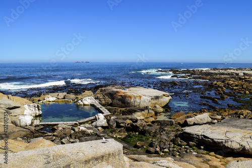 Many rocks, the sea and a tide pool in Saunders' Rocks Beach, Cape Town, South Africa.
