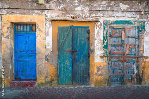 Three colourful yet decayed doors on the streets of the historic old town of Essaouira, Morocco. © Stephen