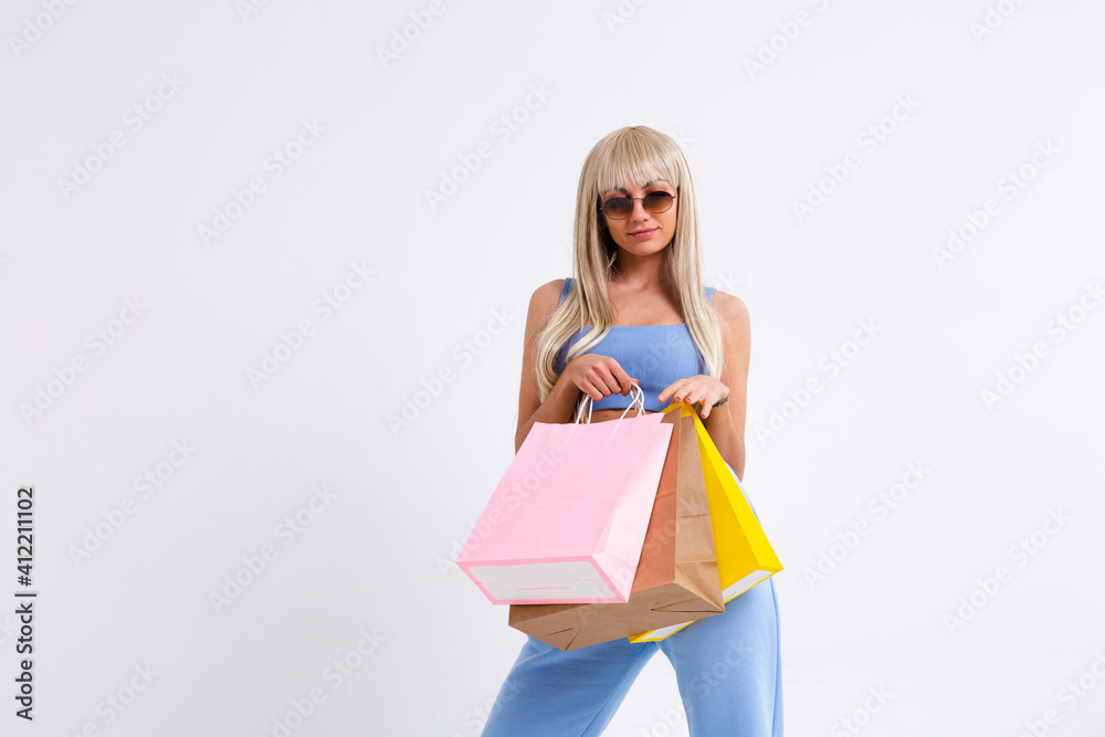 Fashion portrait of young happy blonde woman with long gorgeous straight hair with colorful shopping bags in the studio on a white background. Fashion portrait of young happy blonde woman with long gorgeous straight hair with colorful shopping bags in the studio on a white background.