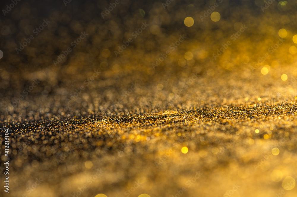 Gold glitter texture on black background. Sparkling gold bright bokeh from blurred diamond dust. Abstract golden bokeh background. Selective focused