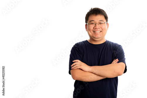 Happy chubby asian man wearing glasses and navy blue t-shirt smiling and standing with crossed arms isolated on white background