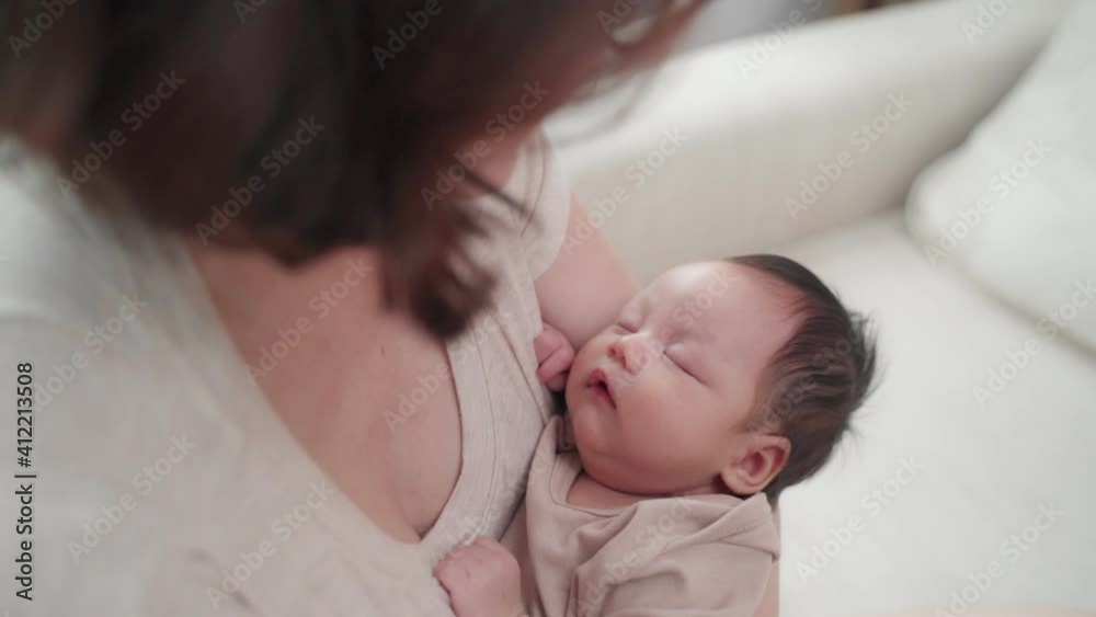 asian woman mother embracing baby on body looking at infant with love emotion. female parent holding and talking to sleeping daughter at home. asian woman mother embracing baby on body looking at infant with love emotion. female parent holding and talking to sleeping daughter at home.