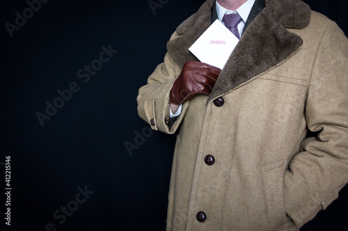 Portrait of Man in Fur Coat and Leather Gloves Pulling Confidential Envelope Out of Coat. Concept of Film Noir Secret Agent Spy Hero. Detective on Case.