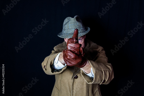 Portrait of Man in Hat and Coat Pointing Finger Gun at Camera. Concept of Film Noir Secret Agent Spy Hero. Detective on Case. Theft and Crime.