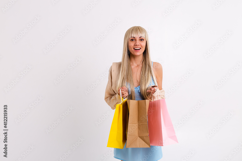 Fashionable portrait of a slender blonde with long hair in a light blue dress and a corduroy shirt with a shopping bag in the studio on a white background Fashionable portrait of a slender blonde with long hair in a light blue dress and a corduroy shirt with a shopping bag in the studio on a white background