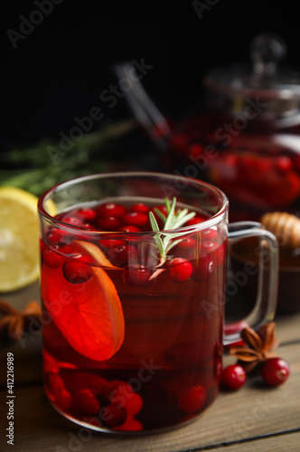 Tasty hot cranberry tea with rosemary and lemon on wooden table