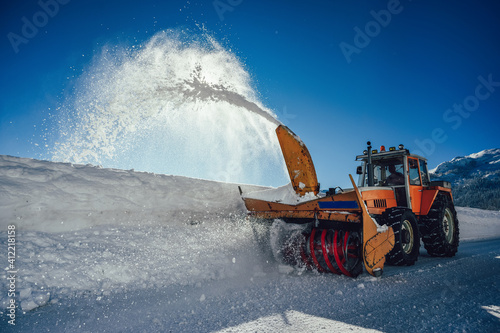 Photos A snowplow truck removing snow from a winding rural road on sunny winter day
