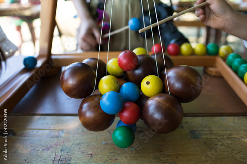 "Suspens", traditional wooden game of Picardie, France with suspended big brown balls and some colorful wooden balls to be added one by by with a stick.