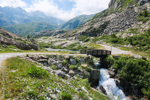 Ponte in legno che attraversa il fiume e bellissima vista sulle montagne dal sentiero che porta ai laghi Cornisello nella Val Nambrone in Trentino, viaggi e paesaggi in Italia