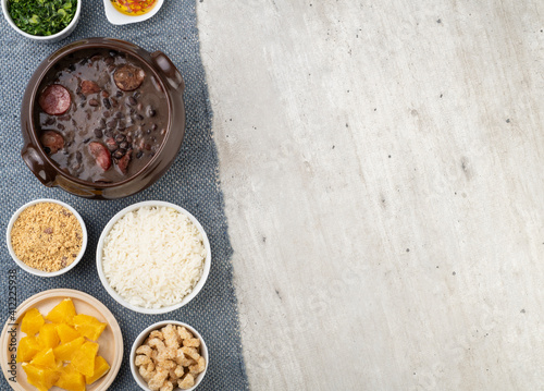Traditional brazilian feijoada with rice, kale, orange, cracklings, manioc flour and copy space