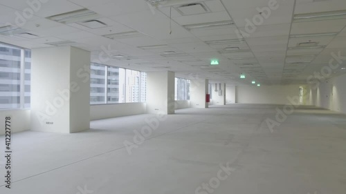 Handheld, camera moving forward – an unfurnished empty office space interior in a city high-rise after tenant move out. COVID-19 cause office space reduction. 