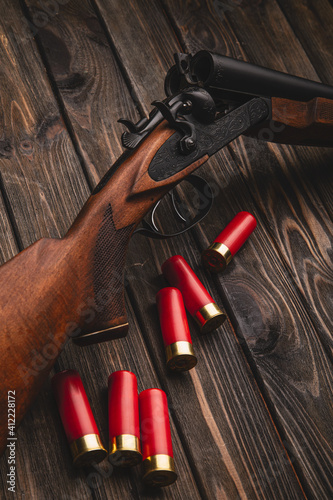 Close-up shot of a loaded vintage double-barreled shotgun with triggers on a wooden background, soft focus