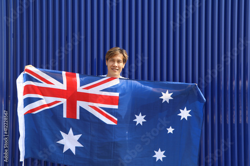 The man is holding Australia fabric flag in his hands on blue background.