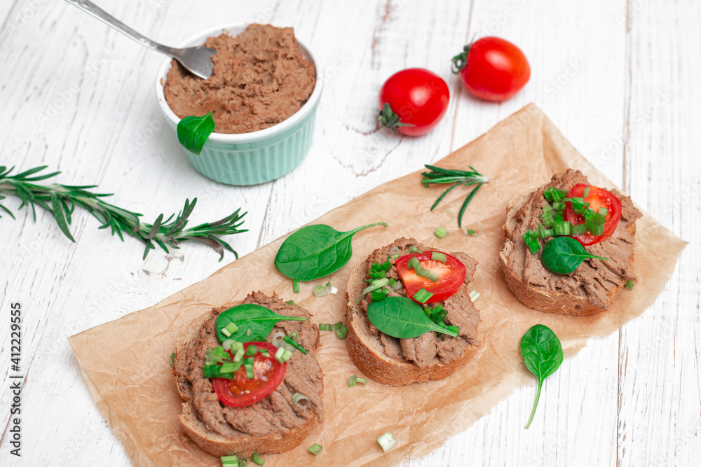 Sandwiches, canapes with chicken pate, tomatoes. On a white wooden background.