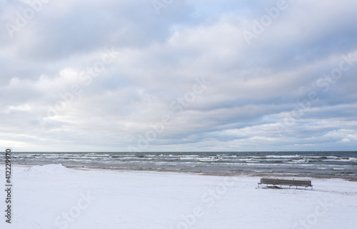 Winter landscape on the coast of the Gulf of Riga with an empty beach bench.
