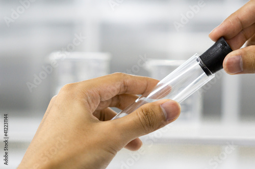 Female hand holding glass tube on science laboratory background.