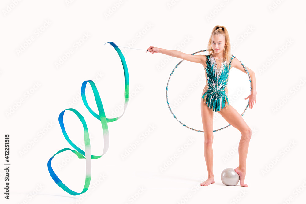 Smiling girl professional gymnast in an emerald swimsuit poses with ribbon, hoop and ball isolated on white background Smiling girl professional gymnast in an emerald swimsuit poses with ribbon, hoop and ball isolated on white background