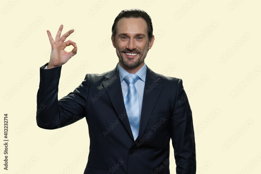Cheerful middle-aged businessman showing ok gesture. Sign good isolated on yellow background. Cheerful middle-aged businessman showing ok gesture. Sign good isolated on yellow background.
