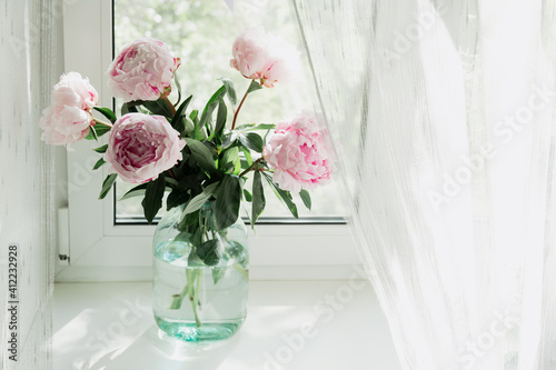 A view of a bouquet of pink peonies standing in a vase on the window. Concept background, flowers, holiday.